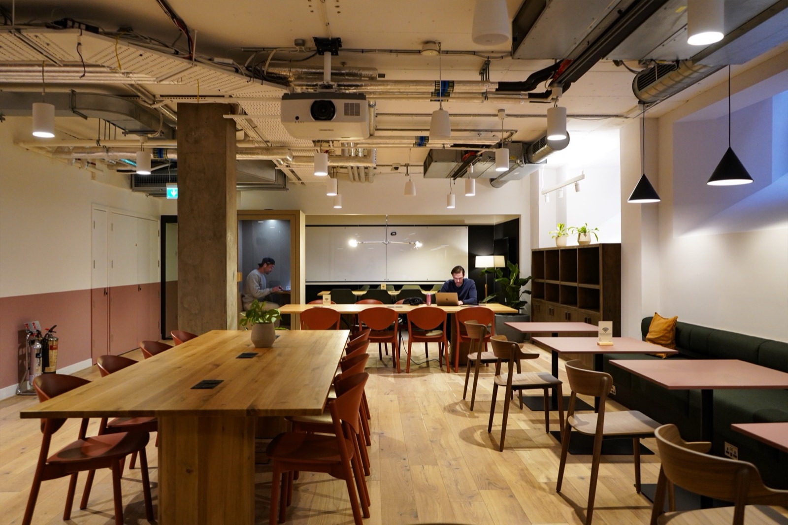 Wooden communal tables and terracotta chairs in the Juntos coworking lounge