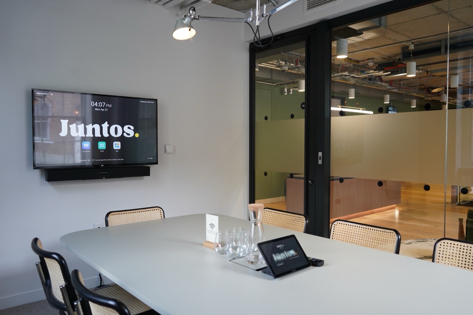 Meeting Room One at Juntos Bedford Row — eight-seat table with presentation screen and Juntos branding